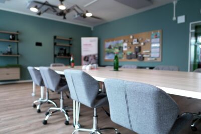 Stühle an großem Tisch, Kreativmaterial & Regale im Hintergrund