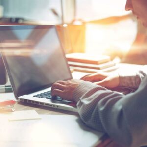 Person sitzt vor Laptop und tippt