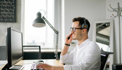 Mann an Computer telefoniert mit Headset