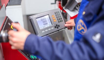 Person in Arbeitskleidung an einer Fräsmaschine