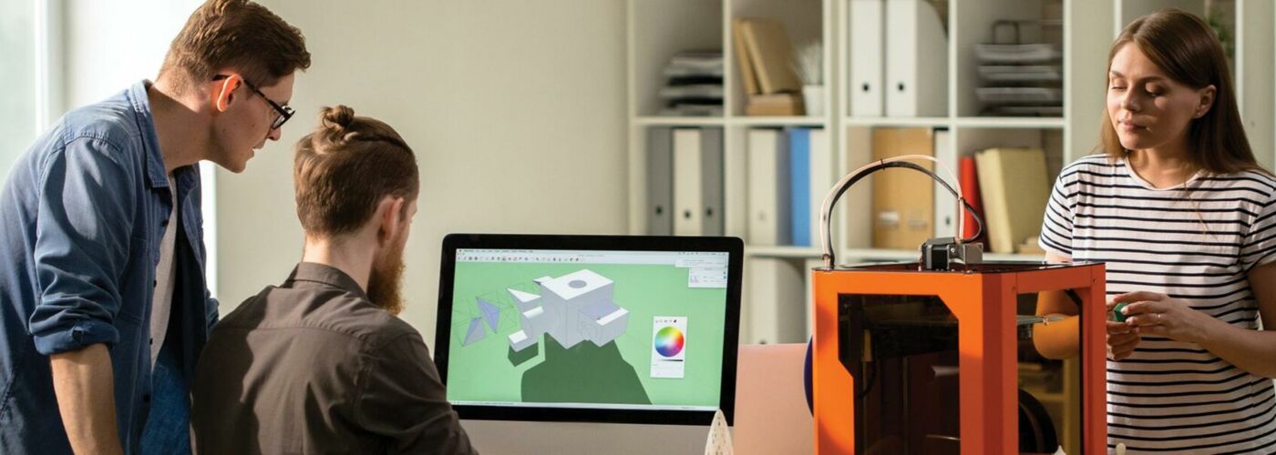 Zwei Männer und eine Frau benutzen einen 3D-Drucker
