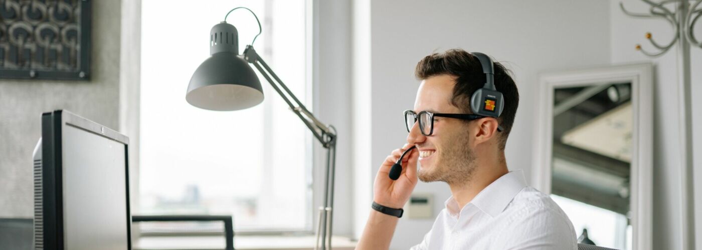 Mann an Computer telefoniert mit Headset