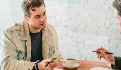 Mann sitzt an Tisch und unterhält sich