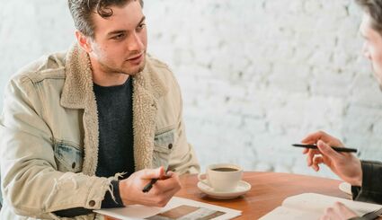 Mann sitzt an Tisch und unterhält sich