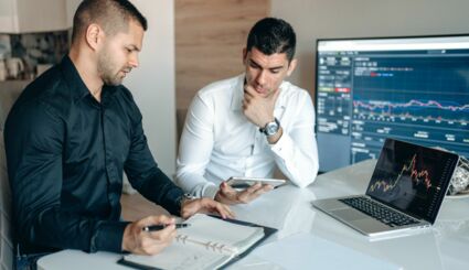 Männer an Tisch mit Laptop und Tablet