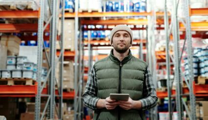 Mann mit Tablet in der Hand steht in einem großen Lager