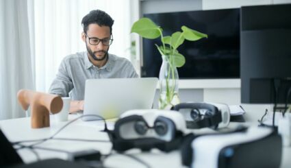 Mann an Tisch mit Laptop und VR-Brillen