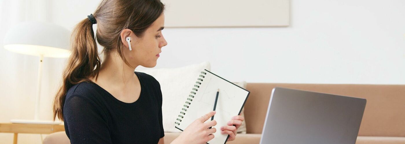 Frau zeigt Notizen in Videochat am Laptop