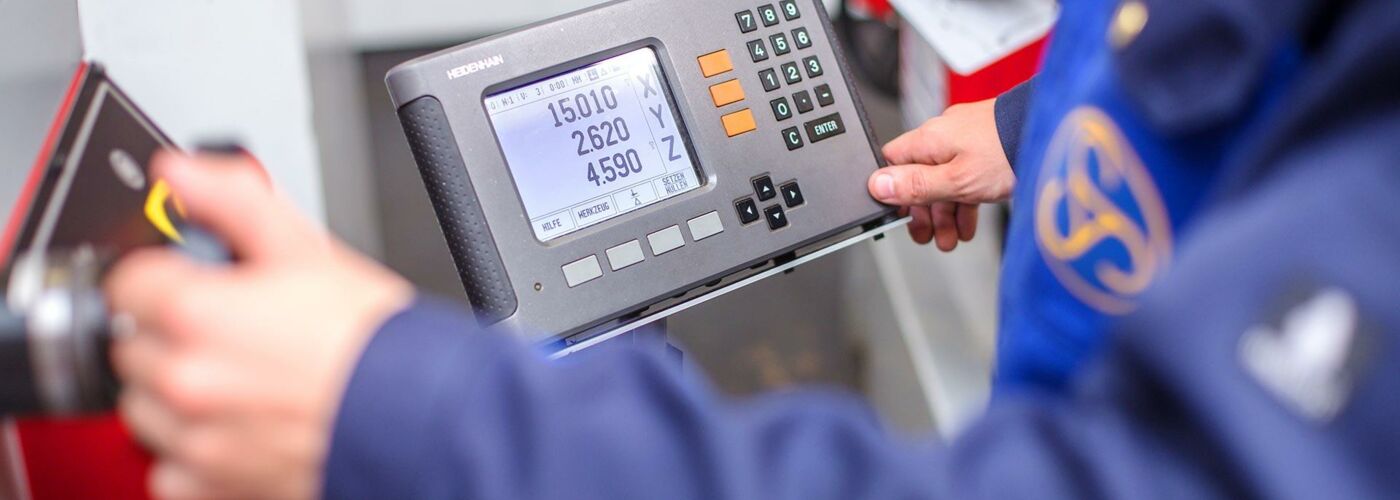 Person in Arbeitskleidung an einer Fräsmaschine