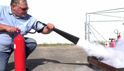 Mann führt Übung zum Gebrauch von Feuerlöschern vor