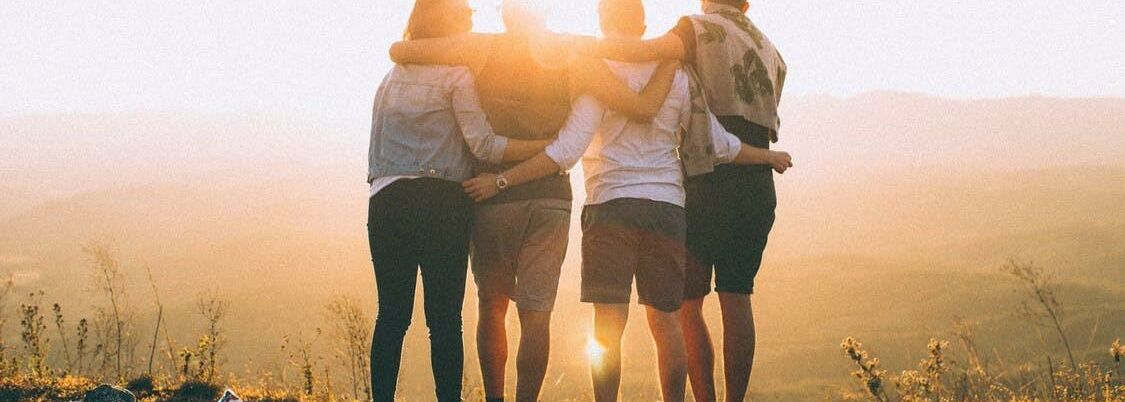 4 junge Menschen liegen sich in den Armen
