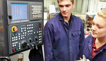 Auszubildende vor CNC-Maschine in Ausbildungszentrum