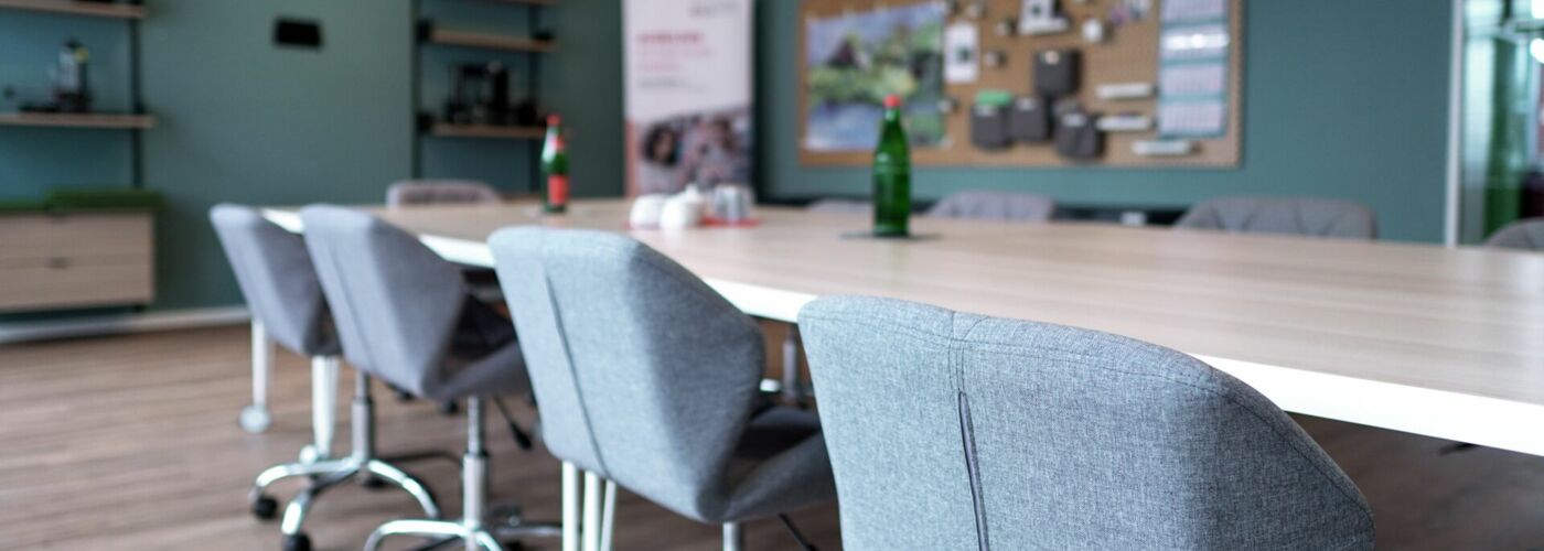 Stühle an großem Tisch, Kreativmaterial & Regale im Hintergrund