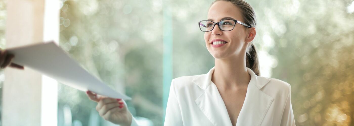 Frau mit Brille überreicht Dokumente