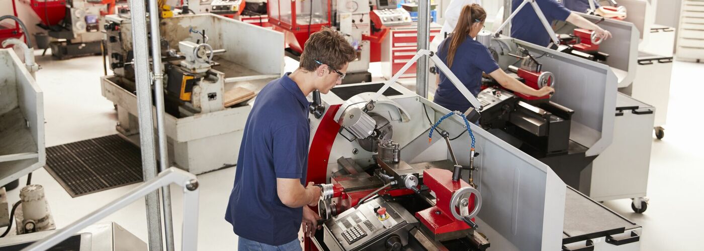 Auszubildende in Werkstatt arbeiten an Drehmaschinen