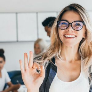 Junge Frau mit Brille lächelt in die Kamera